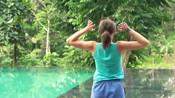 Frau streckt ihre Arme am Pool aus — Stockvideo