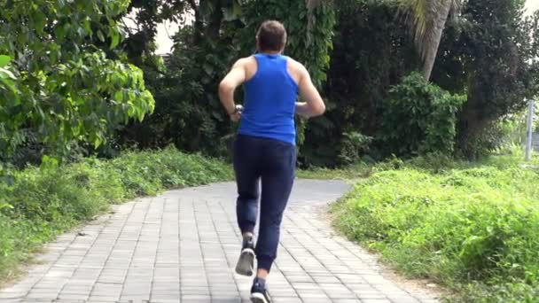 Jongeman joggen op pad in park — Stockvideo