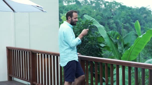 Hombre usando smartphone de pie en la terraza — Vídeo de stock