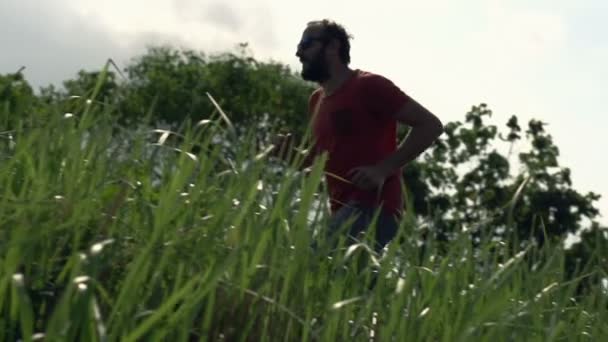 Junger Mann läuft durch Gras — Stockvideo