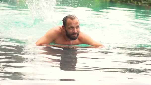 Hombre salpicando agua con las piernas en la piscina — Vídeos de Stock