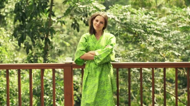 Young woman in bathrobe standing on terrace — Stock Video