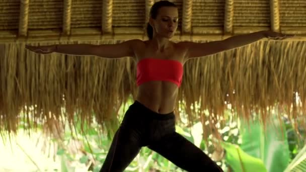 Mujer haciendo la pose del yoga del warior, ejercitando en estera — Vídeo de stock