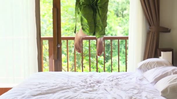 Щаслива жінка в халаті стрибає на ліжку — стокове відео