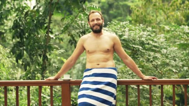 Lykkelig, ung mand i håndklæde på terrasse – Stock-video