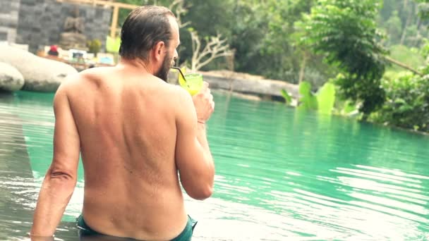 Homme assis près de la piscine et boire un cocktail — Video