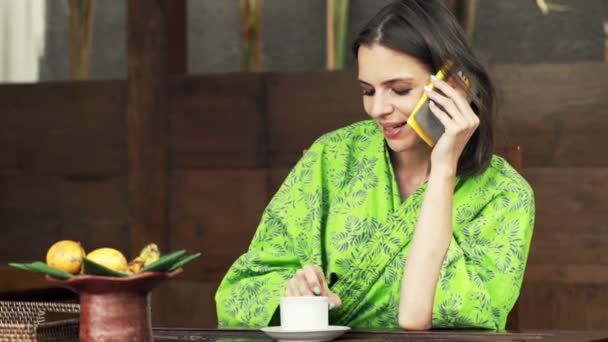 Vrouw praten over cellphone en drinken koffie — Stockvideo