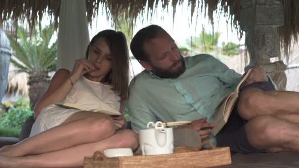 Couple reading books and eating snack on gazebo bed — Stock Video