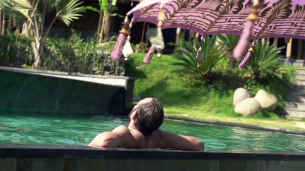 Man relaxing, sunbathing in swimming pool — Stock Video