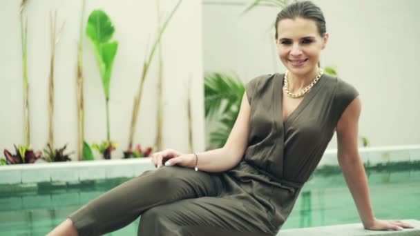 Mujer elegante sentada en el borde de la piscina — Vídeos de Stock