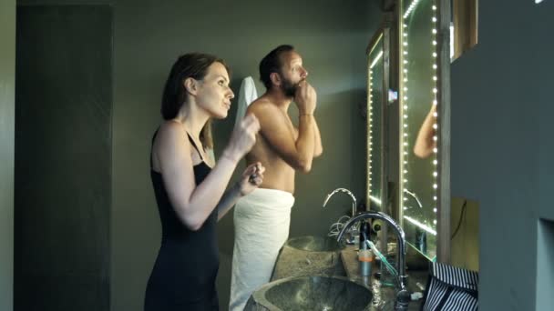 Kvinde gør makeup og mand tjekker hans ansigt – Stock-video