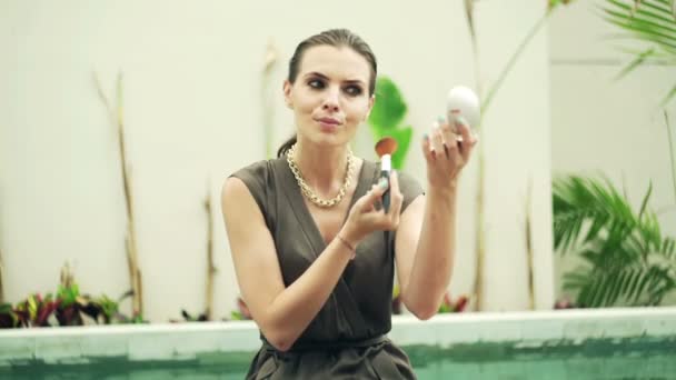 Mujer aplicando maquillaje sentado junto a la piscina — Vídeos de Stock