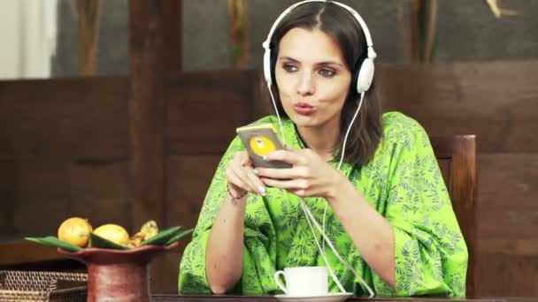 Женщина слушает музыку по мобильному телефону и поет — стоковое видео
