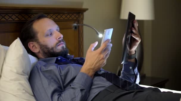 Homme d'affaires travaillant avec tablette et smartphone sur le lit — Video