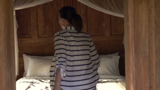 Mujer feliz cayendo en la cama en la habitación — Vídeos de Stock