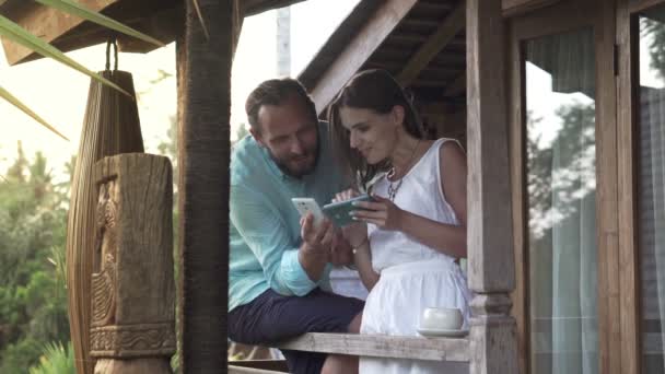 Pareja hablando y usando smartphone en la terraza — Vídeos de Stock