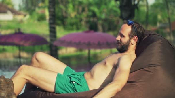 Homme utilisant un ordinateur portable tout en se relaxant au bord de la piscine — Video