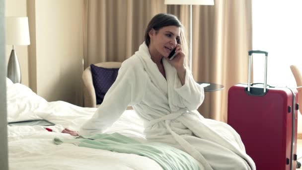 Businesswoman talking on cellphone sitting on bed — Stock Video