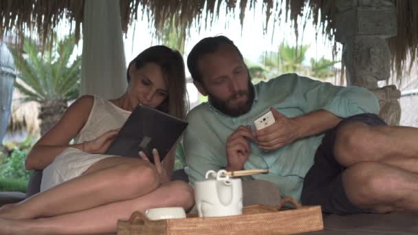 Ζευγάρι χρησιμοποιώντας smartphone και στο tablet στο κιόσκι κρεβάτι — Αρχείο Βίντεο
