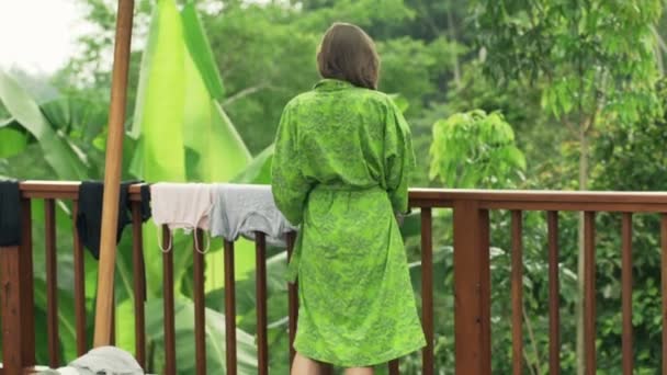 Kvinna med torr tvätt från sladden på terrassen — Stockvideo