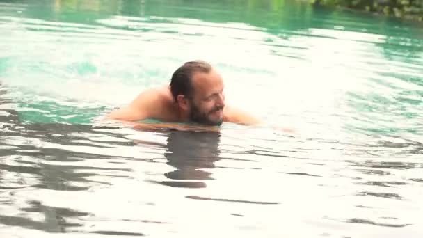 Homem salpicando água com pernas na piscina — Vídeo de Stock