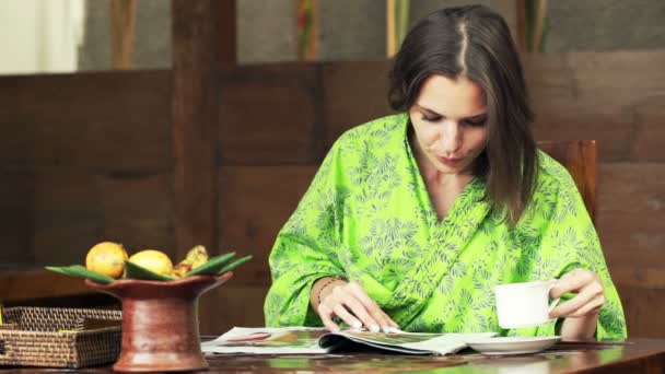 Женщина читает журнал и пьет кофе — стоковое видео