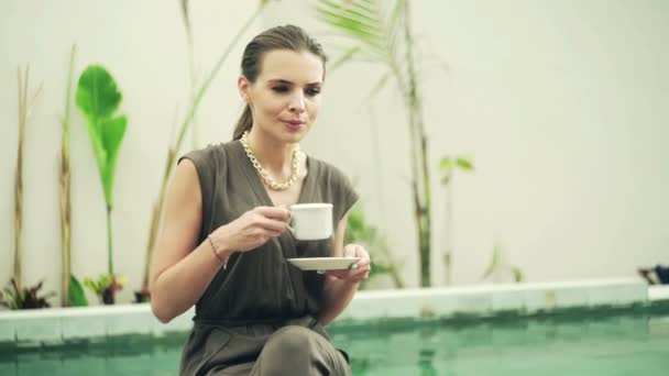 Mujer bebiendo café sentado en la piscina — Vídeos de Stock