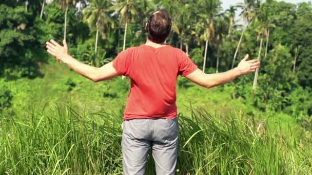 Homem esticando seus braços de pé perto da grama — Vídeo de Stock