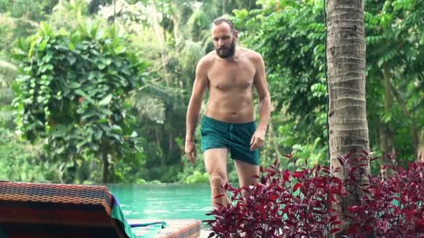 Man drying his body while standing by pool — Stock Video