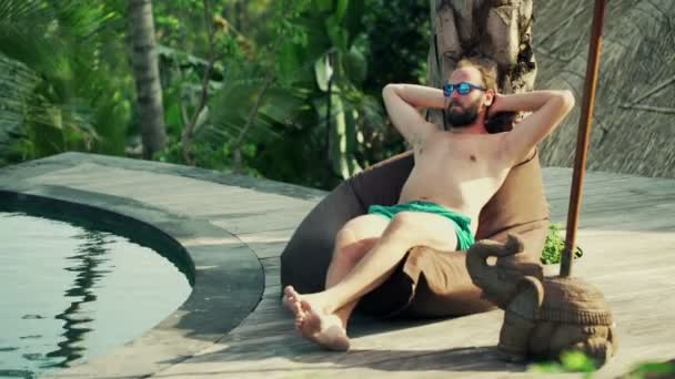 Hombre tomando el sol y relajarse junto a la piscina — Vídeos de Stock