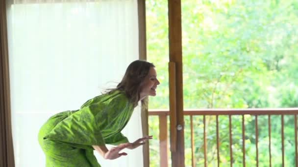 Junge Frau im Bademantel springt auf Bett — Stockvideo
