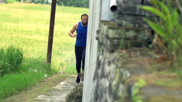 Jeune homme jogging sur le chemin dans le pays — Video