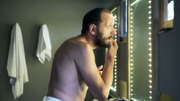 Hombre revisando su cara para las arrugas en el baño — Vídeos de Stock