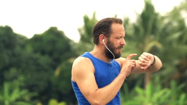 Man jogging and checking pulse on smartwatch in country — Stock Video