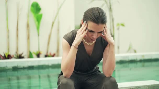 Sad woman sitting on edge of swimming pool — Stock Video