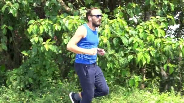 Молодой человек бегает по дорожке в парке — стоковое видео