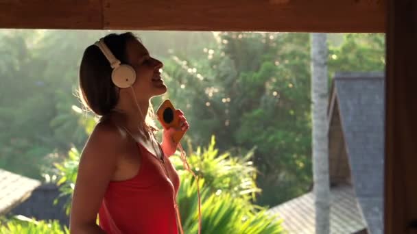 Женщина слушает музыку по мобильному телефону и танцует — стоковое видео