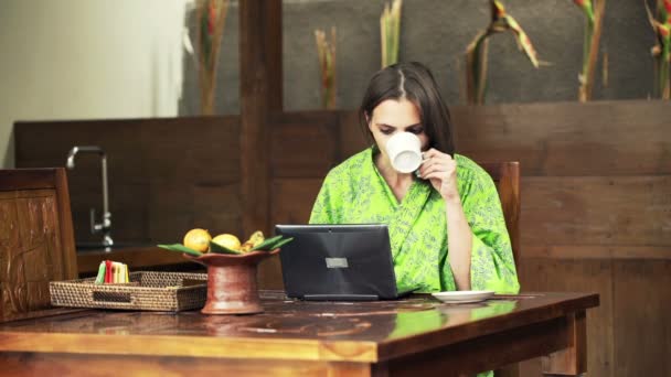 Mujer en albornoz con ordenador portátil y beber café — Vídeos de Stock