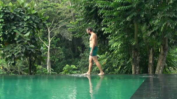 Man walking on the edge of swimming pool — Stock Video