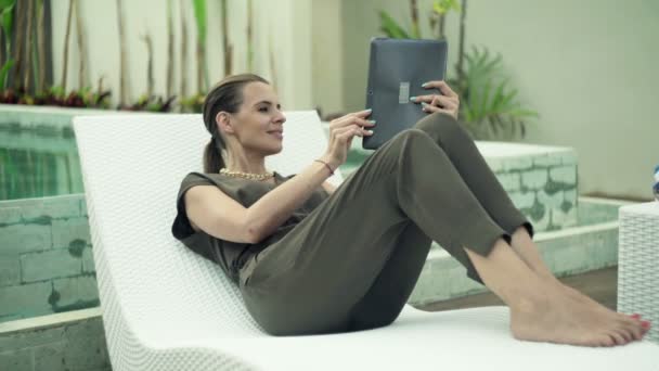 Γυναίκα, κουβέντα στο tablet που βρίσκεται σε ξαπλώστρα — Αρχείο Βίντεο