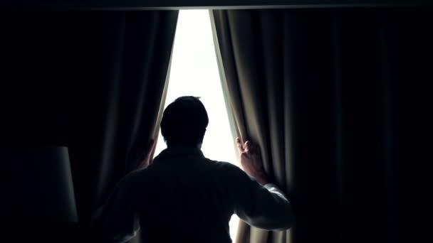 El hombre desvela cortinas y admirar la vista desde la ventana — Vídeos de Stock
