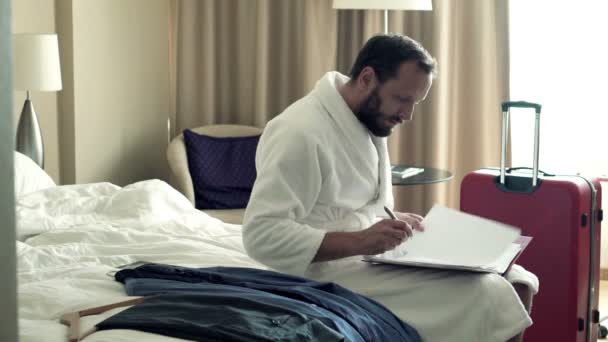 Biznesmen pisanie notatek w dokumentach na łóżku — Wideo stockowe