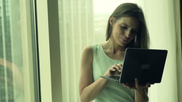Красива бізнес-леді, що працює на ноутбуці вікном — стокове відео
