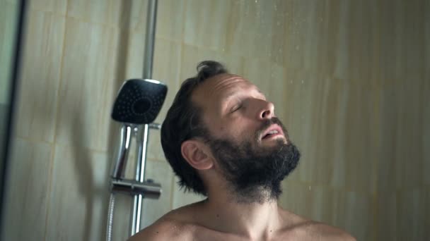 Man washing head and face under shower — Stockvideo