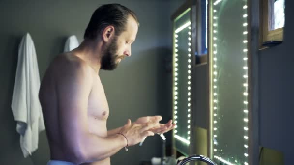 Hombre aplicando crema de belleza en su cara en el baño — Vídeo de stock