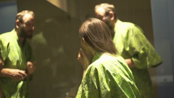 Пара проверяет лицо, ищет морщины в ванной комнате — стоковое видео