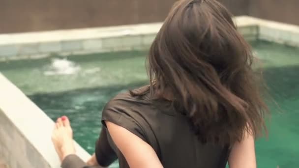 Женщина бросает волосы, расслабляясь у бассейна — стоковое видео