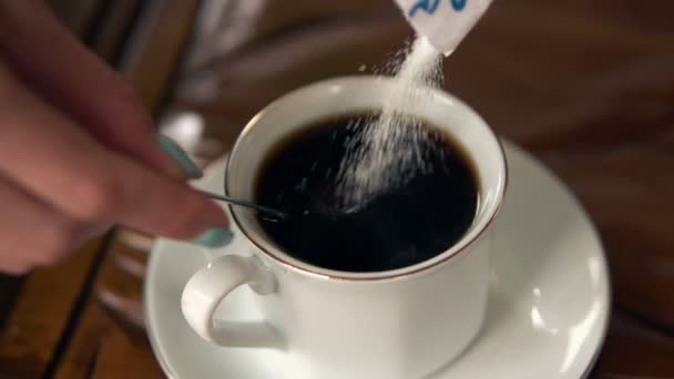 Vrouwelijke hand toevoegen van suiker aan koffie — Stockvideo