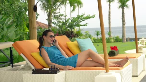 Vrouw praten over cellphone liggend op zonnebank — Stockvideo