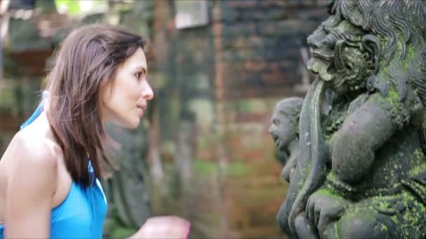 Жінка дивиться на стародавню скульптуру — стокове відео